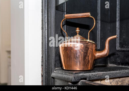 Vintage and antique copper kettle on a Victorian stove in a traditional English kitchen in the UK Stock Photo