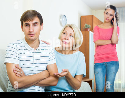 Senior mother-in-law trying to reconcile young couple indoors Stock Photo