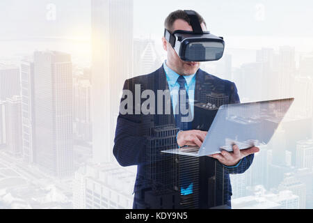 Handsome businessman in VR headset using laptop Stock Photo