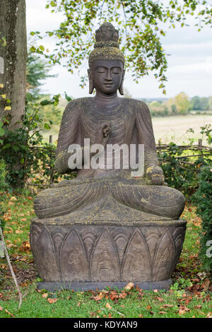 Large stone buddha statue in an english garden. Warwickshire, England Stock Photo