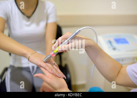 Young woman receiving laser therapy on wrist hand Stock Photo