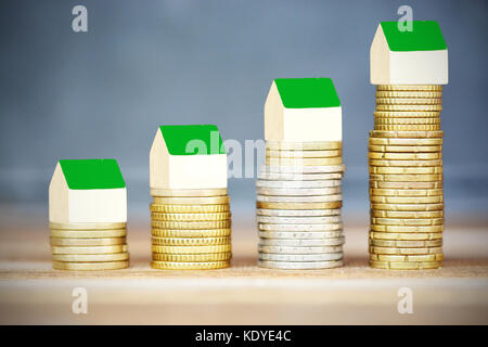 Real estate price evolution concept with miniature wooden houses on ascending piles of money Stock Photo