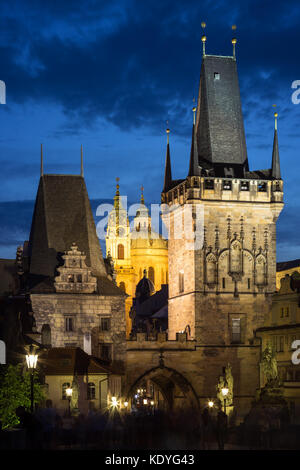 View of the lit Lesser Town Bridge Towers and St. Nicholas Church at the Mala Strana (Lesser Town) in Prague, Czech Republic, in the evening. Stock Photo