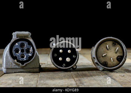 Old plug and socket high voltage. Old electrical accessories. Wooden table, black background Stock Photo