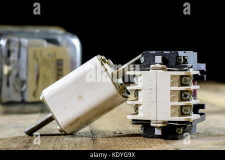 Old ceramic fuse holders. Old electrical accessories. Wooden table, black background Stock Photo