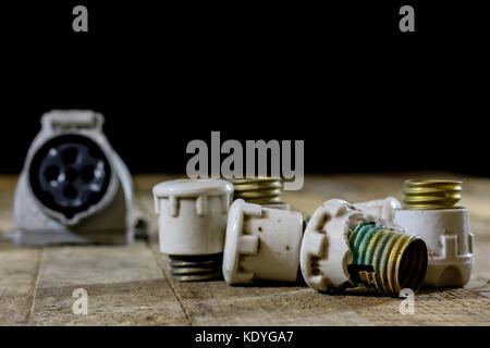 Old ceramic fuse holders. Old electrical accessories. Wooden table, black background Stock Photo