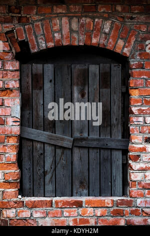 Old boarded up windows in a red face brick building. Stock Photo