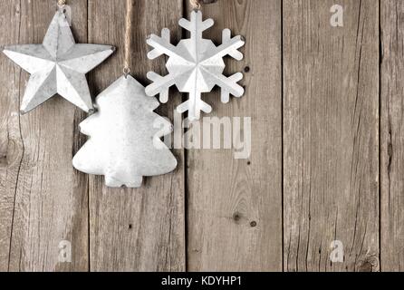 Rustic metal Christmas ornaments hanging on an aged wood background Stock Photo