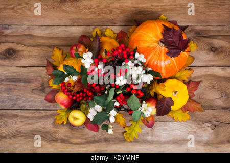 Thanksgiving table centerpiece with snowberry and rowan berries, pumpkins, apples on the rustic wooden background Stock Photo