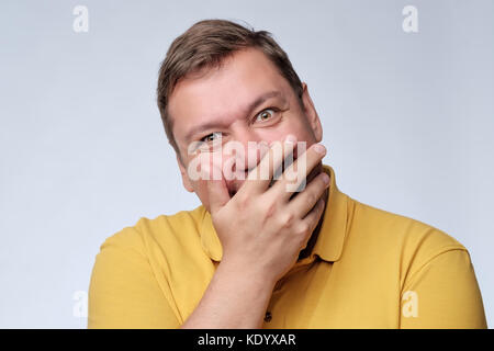 Mature fat man studio portrait. He closes his mouth with delight. Stock Photo