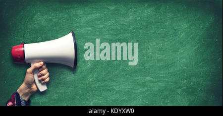 hand with megaphone on blank green chalkboard background Stock Photo