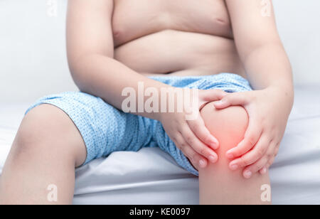 Obese fat boy suffering from knee pain and sit on bed, Healthy problem Stock Photo