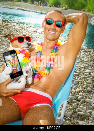 jack russell dog with owner wearing funny fancy red sunglasses, lying on hammock or beach chair lounger together as lovers or friends, on summer vacat Stock Photo