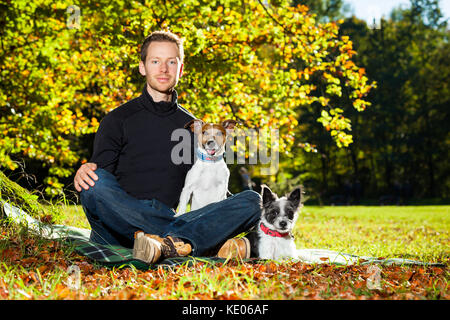 two happy dogs with owner sitting on grass in the park Stock Photo