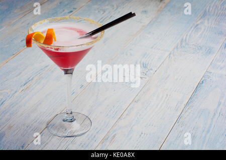 Closeup glass of cosmopolitan cocktail decorated with orange on wooden bar background with copy space. Stock Photo