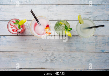 Colorful cocktails. Mojito, Red Cocktail with ice and lime, Margarita, Cosmopolitan on wooden table close up . Stock Photo