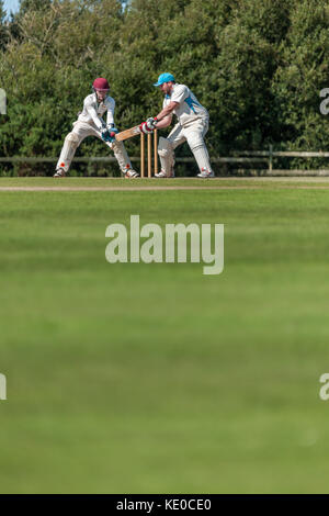 A batsman plays a shot during a Sunday League match between two local Cricket teams. Stock Photo