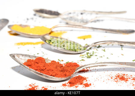 different kinds of dried spices on metal spoons Stock Photo