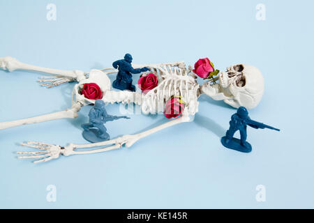 Plastic toy Soldiers arround a pop skeleton wearing flower roses on a pop vibrant blue background. Minimal color still life photography Stock Photo