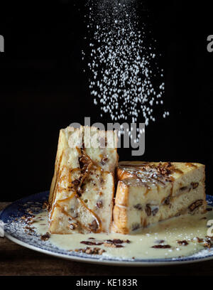 Jumbo french toast stuffed with bananas, roasted pecans and caramel on rustic background Stock Photo