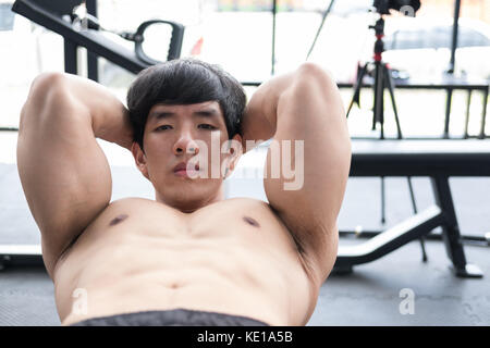young muscle man doing sit up in gym. bodybuilder male working out in fitness center. athlete doing abdominal crunch exercises in health club. sport, 