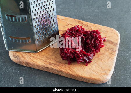 Grated boiled beetroot on an olive wood cutting board. Stock Photo