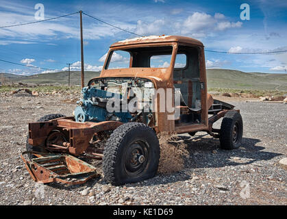 A solitary old pickup truck, abandoned in a gravel parking lot and exposed to the elements in Eastern Washington, is rusting while being scavenged for Stock Photo