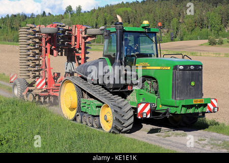 SALO, FINLAND - MAY 27, 2016: John Deere 9520T agricultural crawler tractor and cultivator moving along rural road on the way to cultivate a stubble f Stock Photo