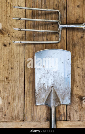 Stainless steel fork and spade, overhead on old wooden background. Stock Photo