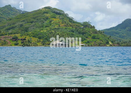 South Pacific island Huahine in French Polynesia coastline with a pearl oyster farm over water in the lagoon Stock Photo