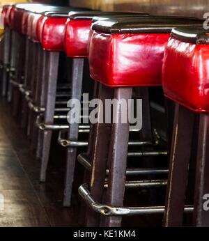 empty red leather barstools lined up in a row at counter Stock Photo