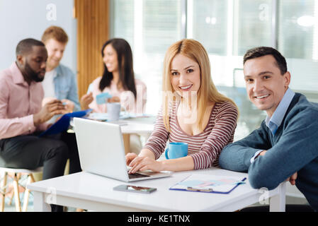 Positive delighted female person helping her coworker Stock Photo