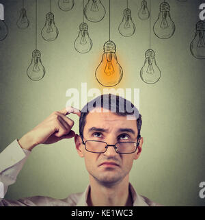 Portrait thinking man in glasses looking up with light idea bulb above head isolated on gray wall background Stock Photo