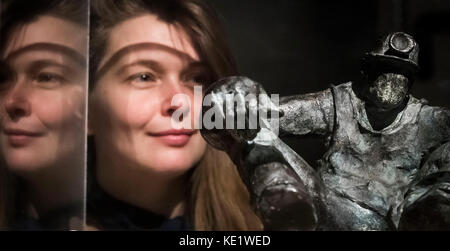Gallery employee Kathryn Wilson is reflected in a display cabinet as she views a bronze sculpture titled Miner by artist Alistair Brookes, during a press preview of the Mining Art Gallery in Bishop Auckland, County Durham. Stock Photo