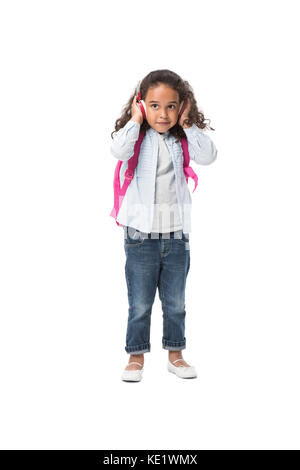 cute african american schoolgirl wearing backpack listening music in headphones isolated on white Stock Photo