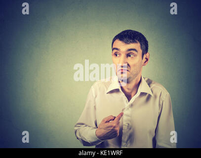 young guy pointing at himself you mean me isolated on gray background. Human emotion facial expression feeling Stock Photo