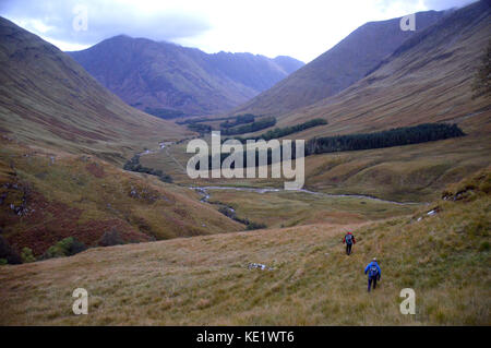 Two Walkers Descending the Corbett Meall Lighiche in Gleann-leac-na-muidhe with the Munros Sgorr nam Fiannaidh and Meall Dearg in Glencoe Just Ahead. Stock Photo