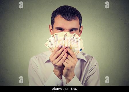 Greedy man with euro banknotes bills isolated on gray wall background Stock Photo