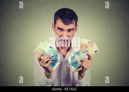 Greedy man with euro banknotes bills isolated on gray wall background Stock Photo