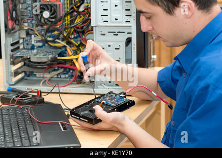 a young technician working on broken computer in his office Stock Photo