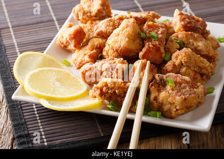 Portion fried chicken karaage with lemon and onion close-up on a plate on the table. horizontal Stock Photo