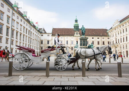 VIENNA, AUSTRIA - AUGUST 28: Tourists in a horse-drawn carriage called Fiaker at the imperial Hofburg palace in Vienna, Austria on August 28, 2017. Stock Photo