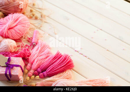 Pink tassels. Background of white wood. Women's handicrafts. The concept of creativity. Stock Photo