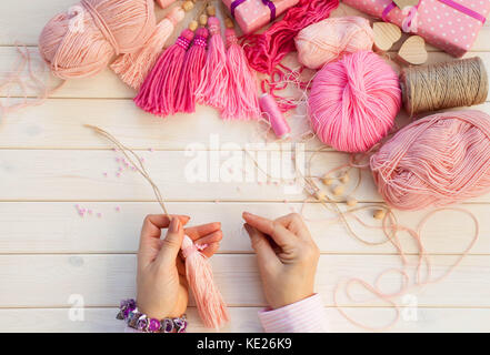 Pink tassels. Background of white wood. Women's handicrafts. The concept of creativity. Stock Photo