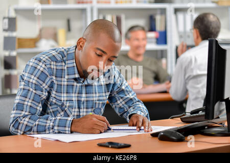 Man sat at desk working on blueprints Stock Photo