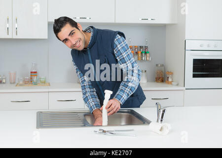 happy male plumber in overall fixing sink pipe Stock Photo