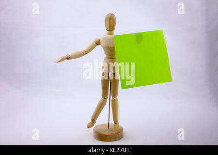 Two green sticky note reminders on a white background hoalding by the wooden sculpture with text copy space Stock Photo