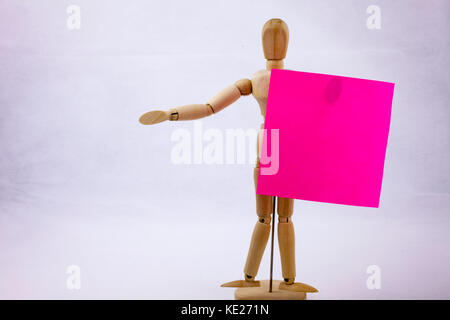 Two pink sticky note reminders on a white background hoalding by the wooden sculpture with text copy space text Stock Photo
