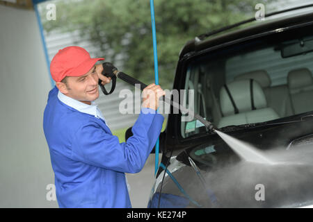 mature man washing a car with pressured water Stock Photo