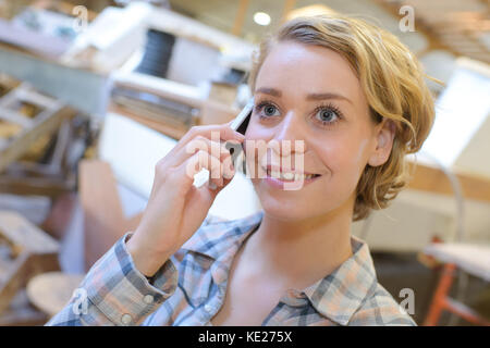 female carpenter smiling while talking on the phone Stock Photo